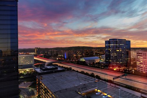 Sunrise over light trails and city lights on a highway in Irvine, California, USA.