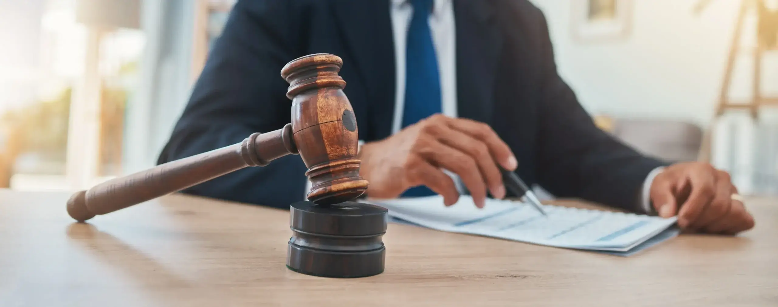 Gavel on a desk beside a lawyer reviewing court documents