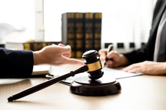 Wooden gavel with a gold band on a desk while Sacramento appellate lawyer discuss documents behind it.